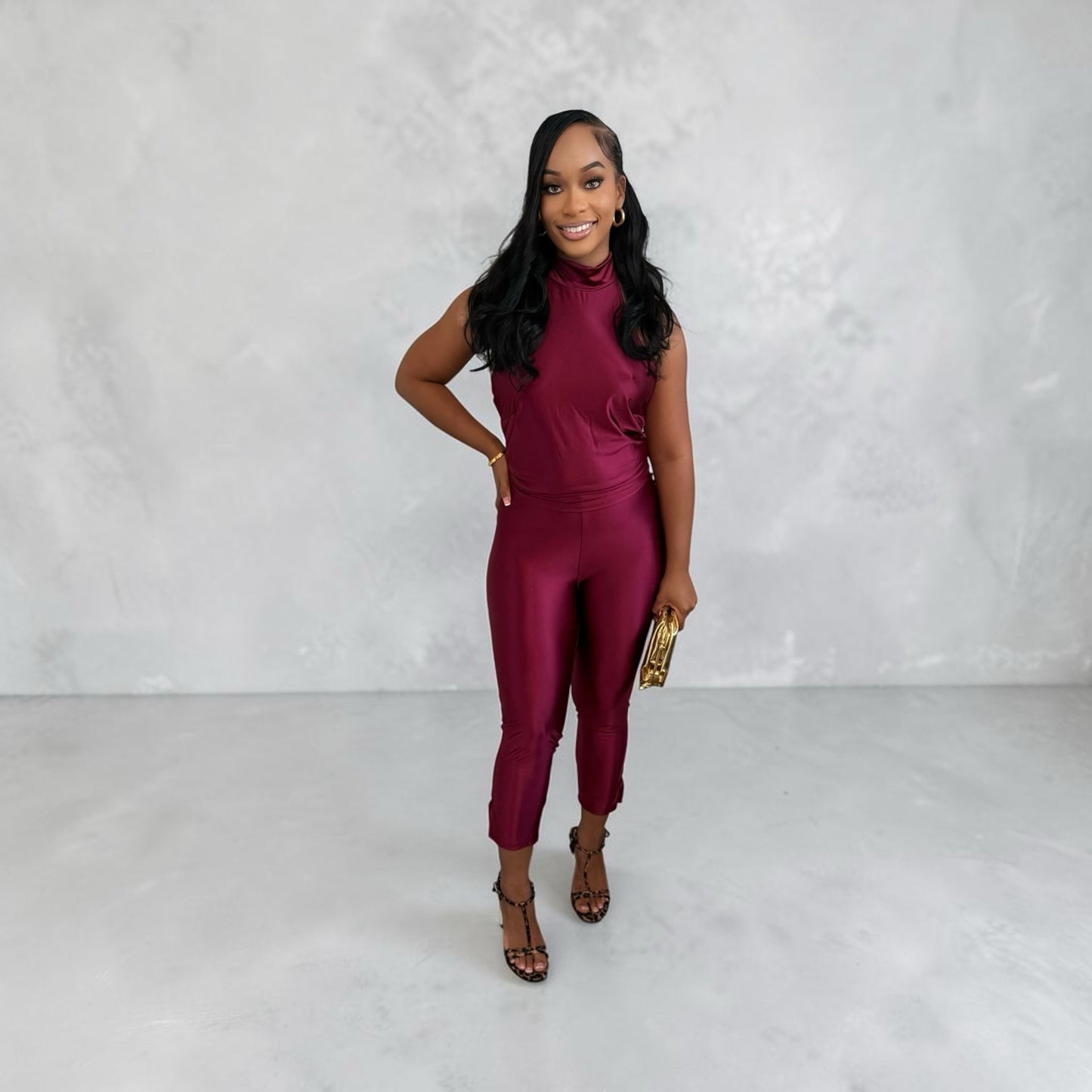 Model wearing an 8.Thirteen burgundy sleeveless mock neck two-piece jumpsuit with a sleek, form-fitting silhouette.