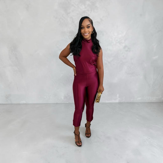 Model wearing an 8.Thirteen burgundy sleeveless mock neck two-piece jumpsuit with a sleek, form-fitting silhouette.